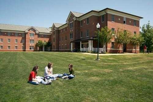 Exterior summer view of Candler Hall with three students studying in the foreground